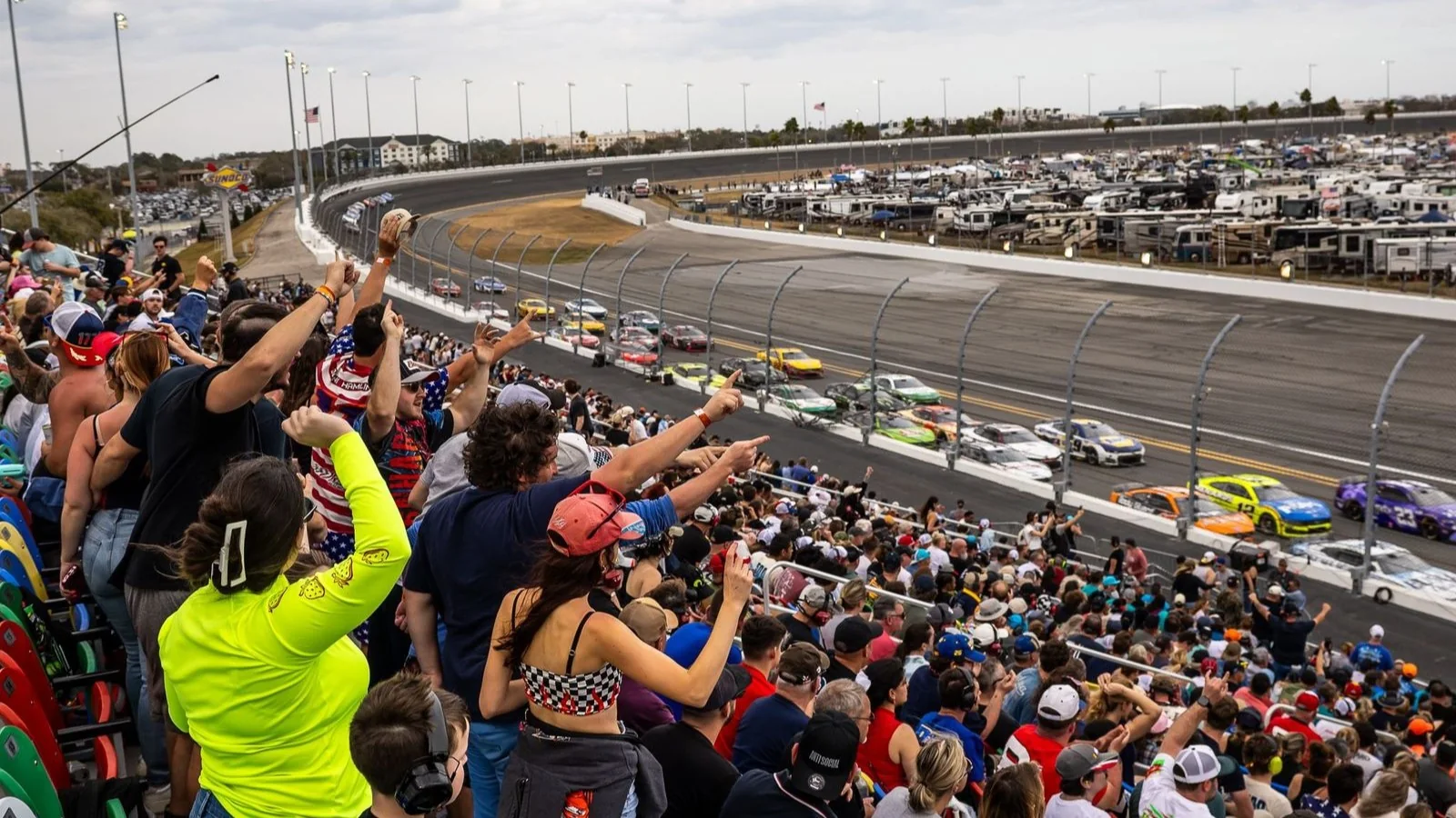 Fans watching the NASCAR Cup field from a Turn 4 grandstand at Daytona International Speedway