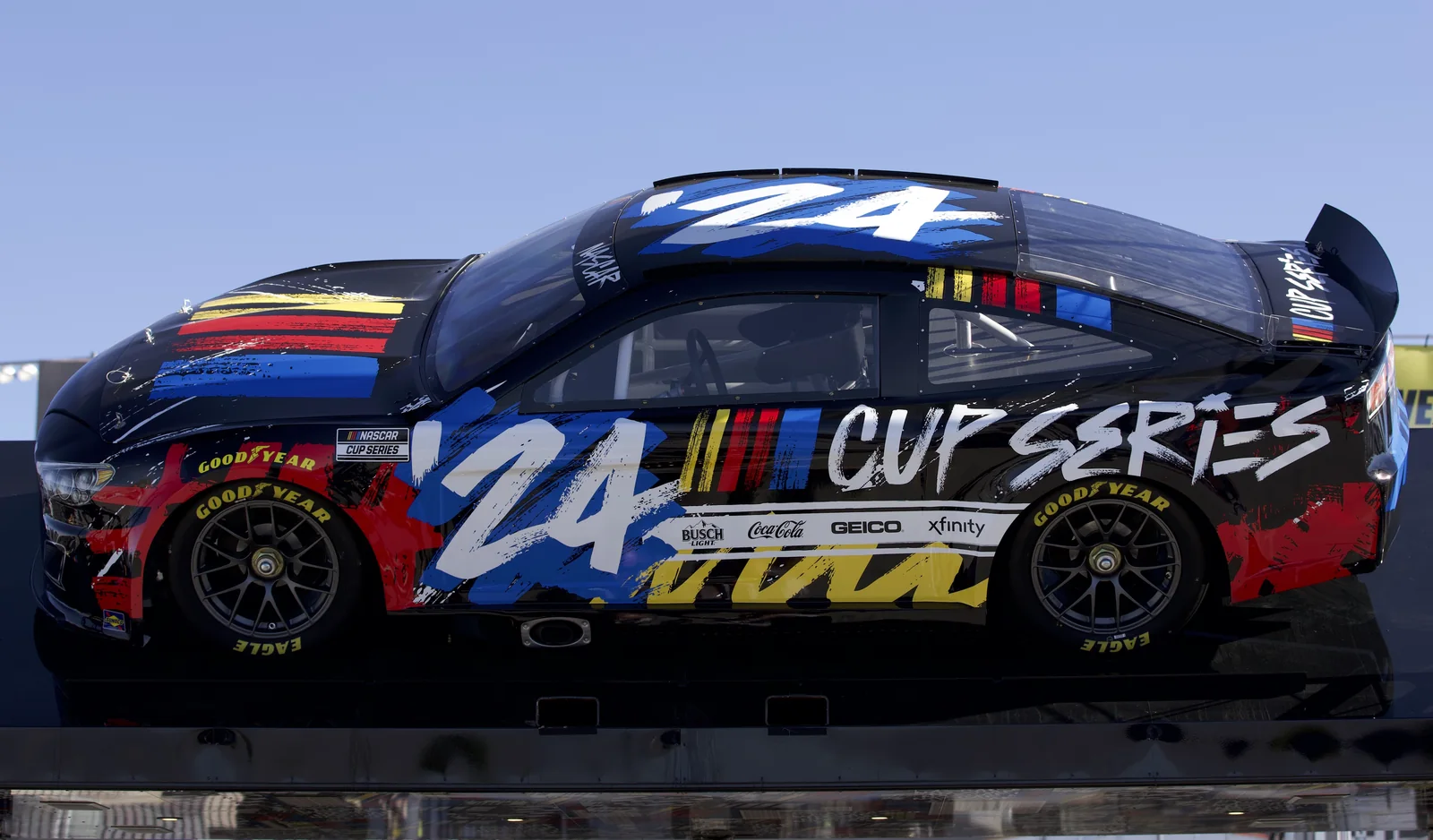Side profile of a number 24 NASCAR Next Gen showcar displaying its coupe shape and center-lock wheels